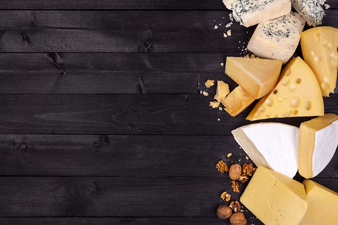 Various types of cheese on black wooden 